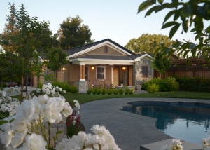 A house with flowers around the pool and trees.