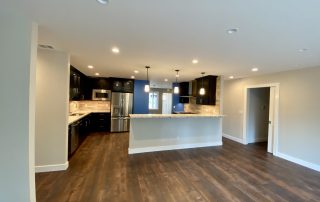 A kitchen with wood floors and dark cabinets.