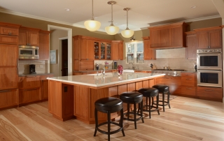 A large kitchen with wooden cabinets and black stools.